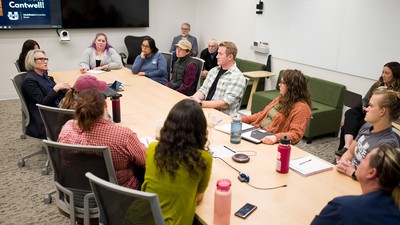 A group of people sit at a table in a discussion.